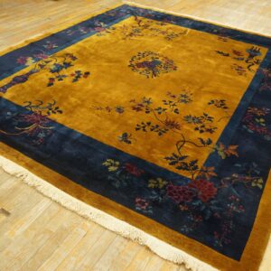 Plush golden yellow rug with a navy blue border and multicolor floral patterns displayed on wood flooring.
