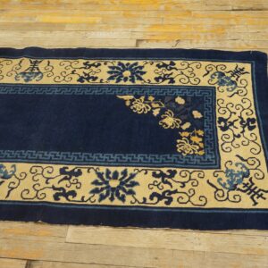Navy blue and pale yellow bordered rug with floral motifs rests on rustic wood planks.