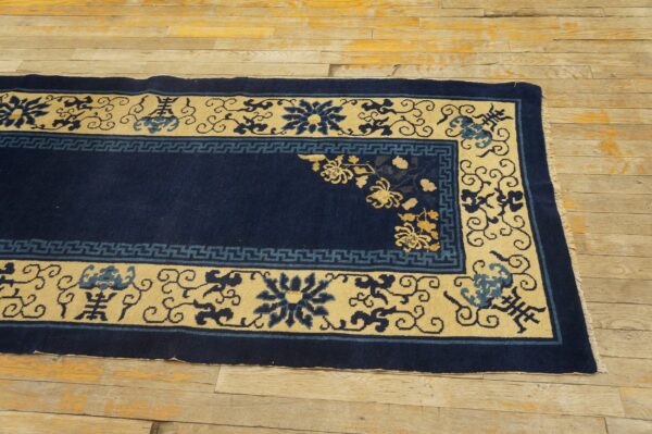 Navy blue and pale yellow bordered rug with floral motifs rests on rustic wood planks.