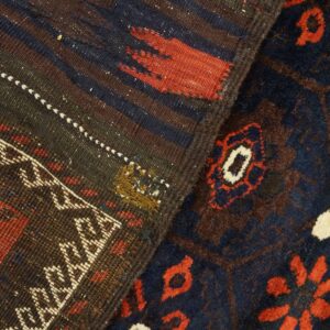 Detail of two rugs showing a dark striped flat weave and a navy, red, and cream high-pile pattern.