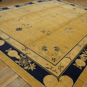 A large gold rug with a wide navy blue patterned border lies on distressed wooden floorboards.