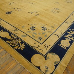 Corner of a golden-yellow rug with navy blue and light blue patterns resting on rustic wood floors.