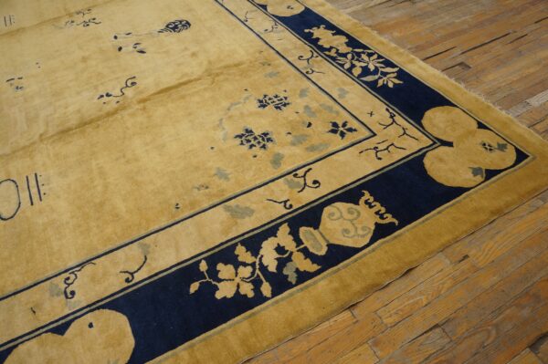A gold rug with stylized navy and light blue designs rests on worn hardwood floors.