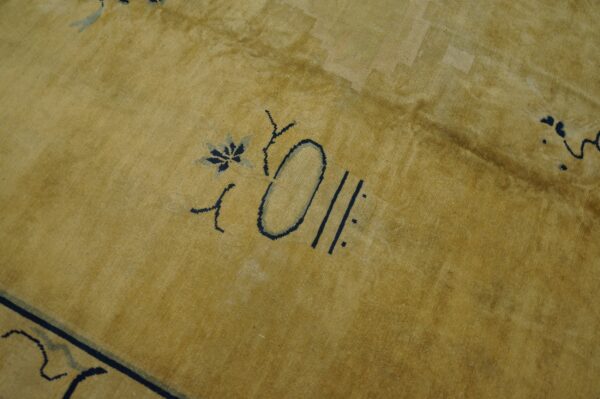 Close-up of a mustard yellow rug featuring stylized navy blue abstract floral motifs.