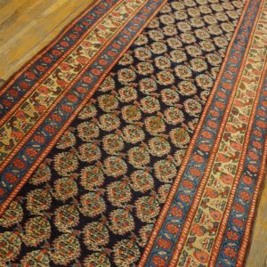 Navy blue runner rug with red, cream, and blue pattern sits on distressed golden wood floorboards.
