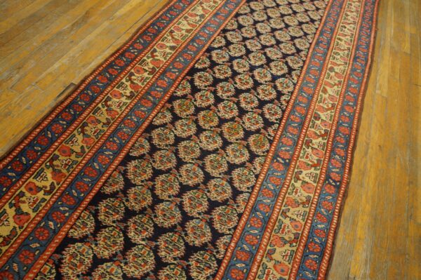Navy blue runner rug with red, cream, and blue pattern sits on distressed golden wood floorboards.