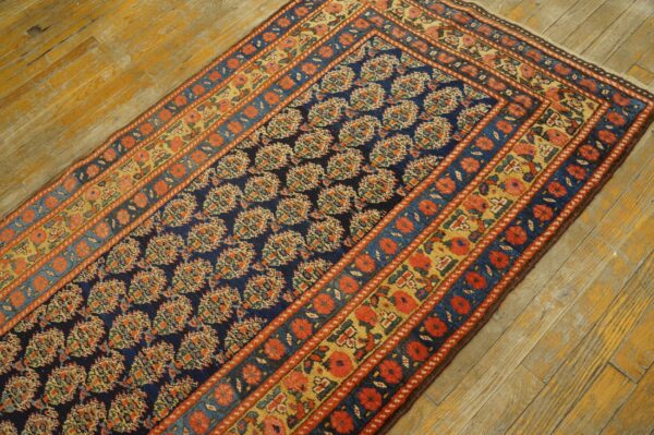 Navy runner with dense floral patterns and orange-red borders rests on rustic, distressed wood flooring.