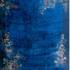 Velvety blue area rug featuring multicolored floral and leaf motifs cascading across the borders.