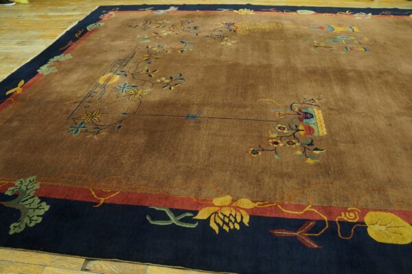Brown rug featuring colorful scattered vines and flowers within a wide navy and red decorative border on wood floors.