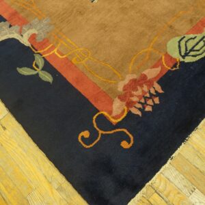 High-pile rug corner featuring navy, tan, and red floral designs resting on distressed yellow wood planks.