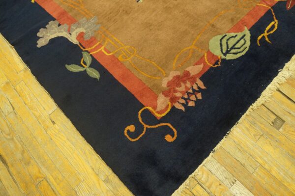 High-pile rug corner featuring navy, tan, and red floral designs resting on distressed yellow wood planks.