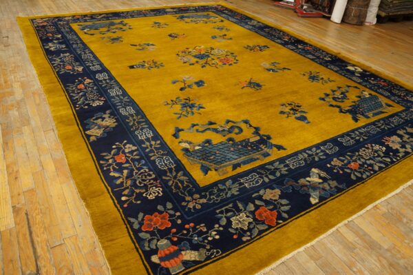 Mustard yellow rug with a navy border displays floral and symbolic patterns on light wood flooring.