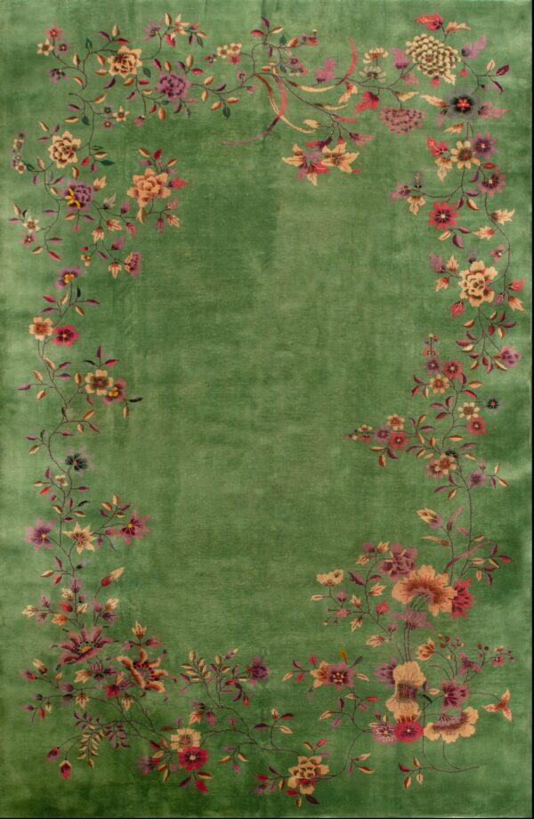 Green rug with a distinct, multicolored floral vine border surrounding a solid center field.