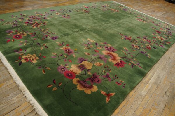 Plush green area rug with pink and gold floral motifs resting on distressed wooden planks.
