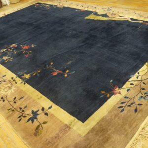 Navy rug with floral and crane motifs, gold and tan borders, displayed on light wood flooring.