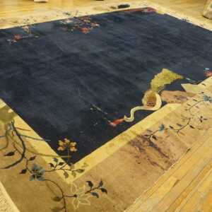 Deep blue rug with an ornate beige border, featuring large flowers and a crane, on hardwood planks.