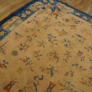 Gold rug featuring scattered blue and coral motifs and a dark blue border, placed on rustic wood flooring.
