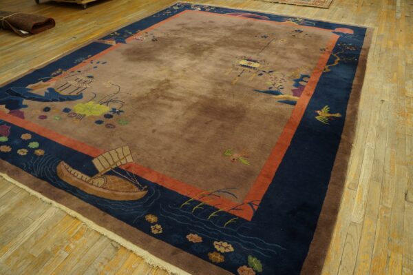 Brown and navy scenic rug featuring boats and birds, framed by an orange border on light wood floors.