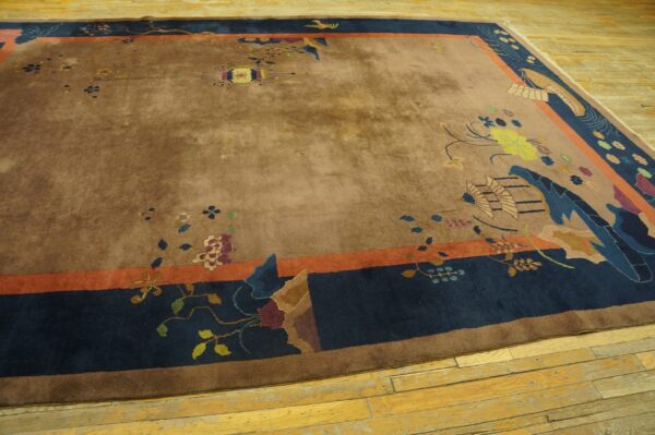 Low-pile brown rug with colorful floral and bird motifs, featuring a dark blue and coral border on wood planks.