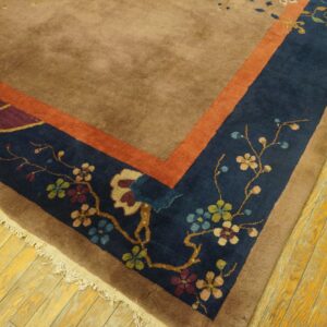Brown rug with burnt orange and floral navy blue borders resting on distressed yellow hardwood floor planks.