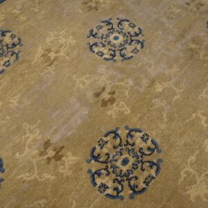 Low pile rug in tan featuring repeating dark blue medallions and tone-on-tone secondary motifs.