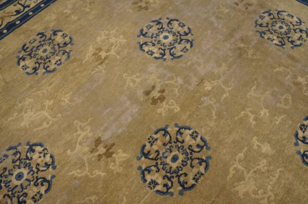 Low pile rug in tan featuring repeating dark blue medallions and tone-on-tone secondary motifs.