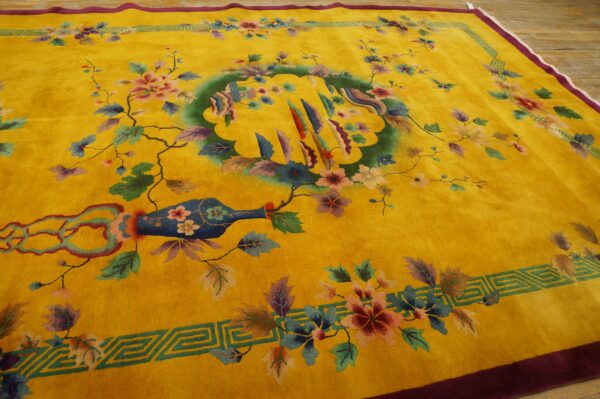 Saturated yellow rug with a colorful floral and vase pattern, maroon edge, and geometric green border on wood.