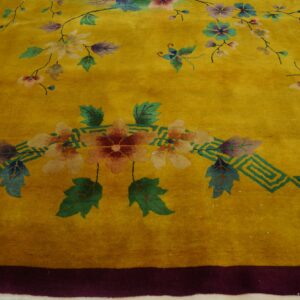 Close-up of a high-pile yellow rug featuring colorful floral and butterfly motifs and a geometric teal border element.