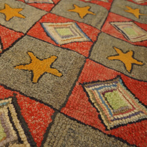 Textured, chunky rug featuring a red and gray grid pattern with orange starfish and multi-colored square patches.