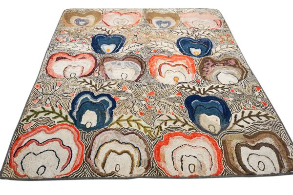 Textured rug with organic, layered blue, coral, and brown floral motifs on a fine-lined white background.