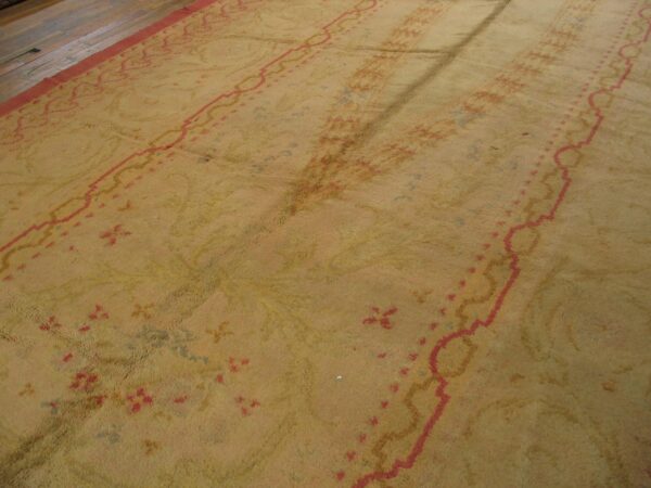 High-pile gold rug with faded coral and blue patterns sits adjacent to dark wood planks.