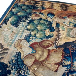Close-up of a flat-woven tapestry rug depicting figures and foliage in deep blue, tan, and muted green.