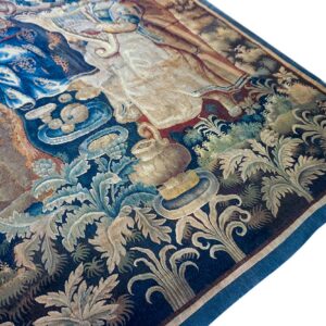 Detailed tapestry featuring figures and botanical motifs in deep blue, cream, and tan on a white background.