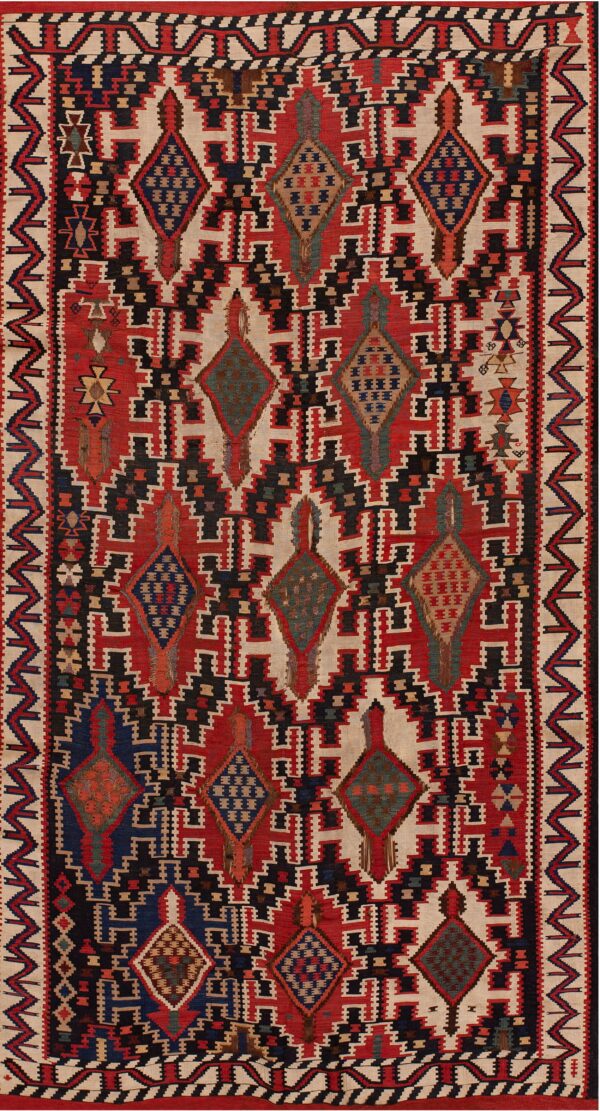 Geometric flatweave rug featuring stepped medallions and interlocking patterns in red, black, cream, and blue.
