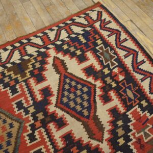 Geometric flatweave rug featuring stepped patterns in red, navy, and cream lying on rustic wood planks.