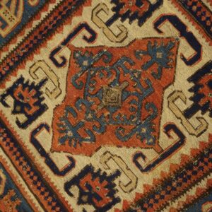 Geometric rug detail featuring stepped designs and borders in indigo blue, terracotta, and cream.