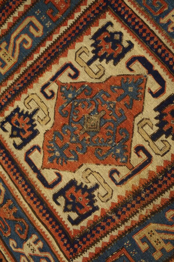 Geometric rug detail featuring stepped designs and borders in indigo blue, terracotta, and cream.