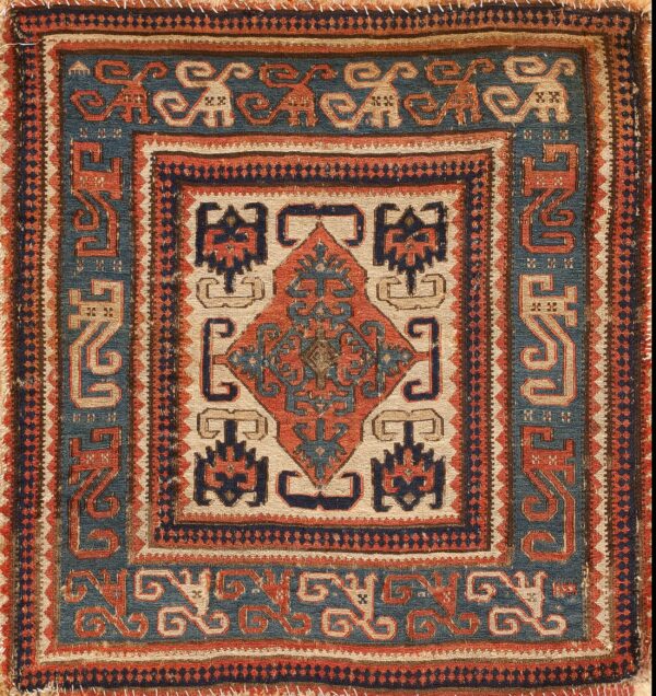 Low-pile geometric rug in indigo blue, rust red, and beige, featuring repeating stylized animal motifs.