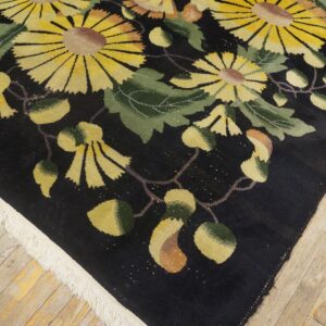 High-pile black rug with bright yellow and green botanical designs on distressed plank wood flooring.