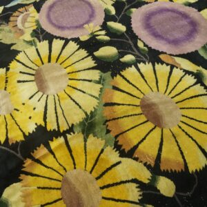 Black rug featuring large scale yellow sunflowers and light purple flowers with green foliage.