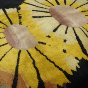 Close-up of a plush rug showing large yellow flower petals and light brown centers against a dark black background.