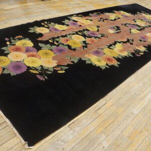 A long black rug features a vibrant floral pattern of yellow, purple, and orange flowers on wood plank floor.