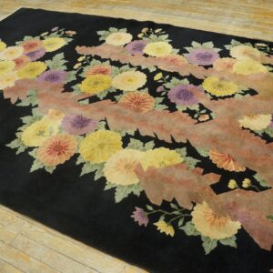 Floral rug featuring yellow, purple, and coral blossoms on a black field with a textured, salmon-colored zigzag design.