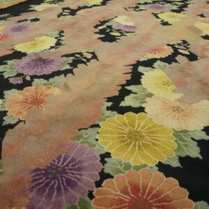 Black rug with large yellow, purple, and coral floral motifs and a central pink abstract pattern.