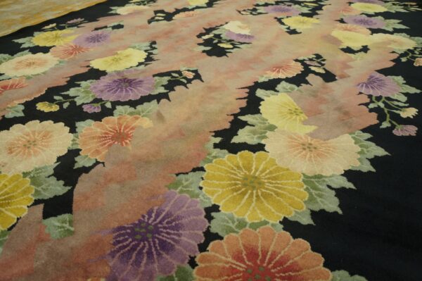 Black rug with large yellow, purple, and coral floral motifs and a central pink abstract pattern.