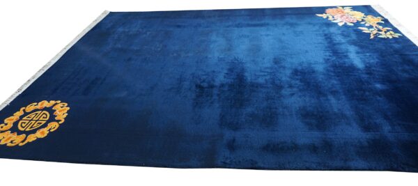 A deep blue plush rug with colorful floral motifs and an orange stylized symbol in opposing corners.