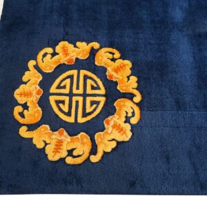 Plush blue rug detail showing an orange geometric circular pattern and surrounding clouds, with white fringe.