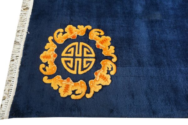 Plush blue rug detail showing an orange geometric circular pattern and surrounding clouds, with white fringe.