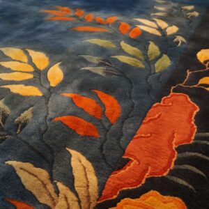 Plush blue rug featuring carved botanical elements in bright orange, gold, and pale green colors.