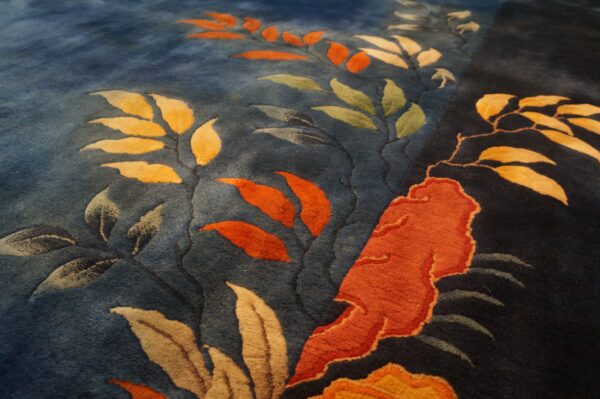 Plush blue rug featuring carved botanical elements in bright orange, gold, and pale green colors.